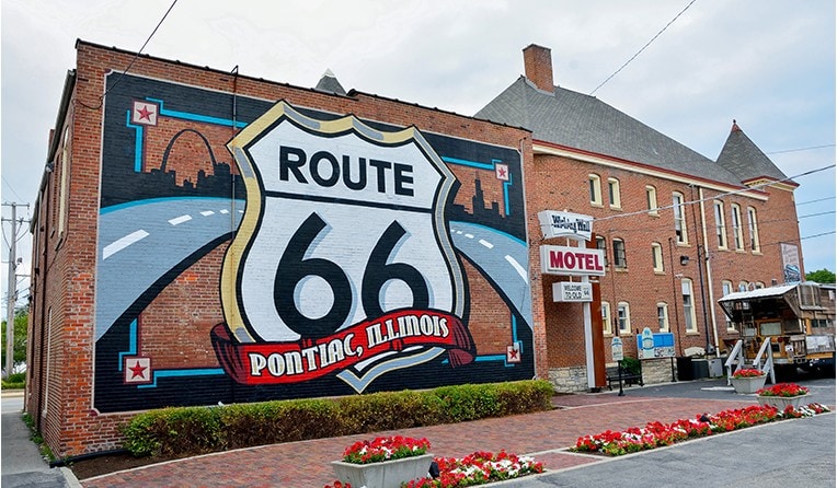 A mural of Route 66 on the side of a brick building, capturing the Illinois Odyssey.