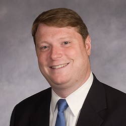 A man named Mark Falzone in a suit and tie smiling for the camera.