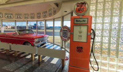 A red and orange car sits in front of a gas pump in Oklahoma, the heart of Route 66.
