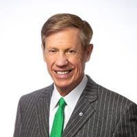 A smiling man in a suit and green tie named Richard Ware.