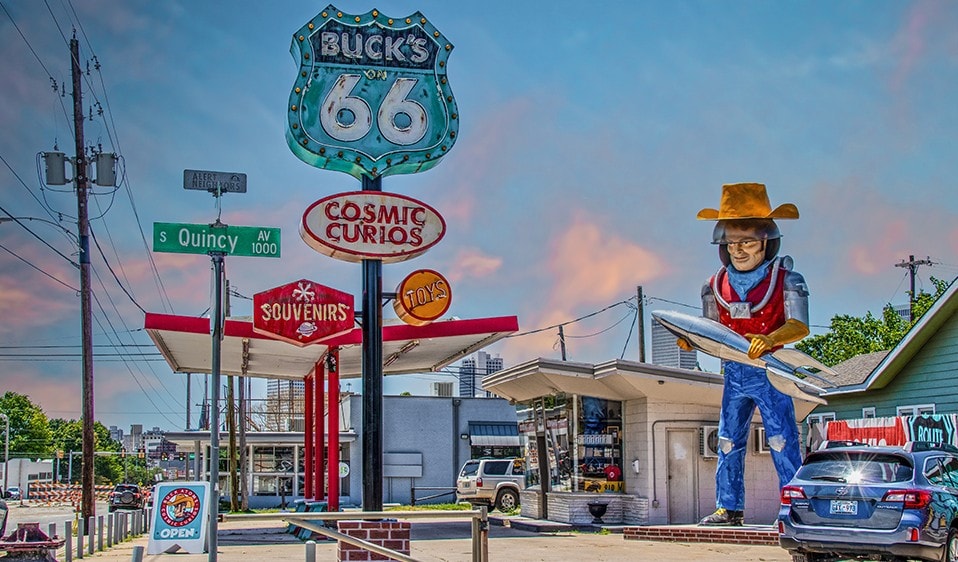 A statue of a cowboy sits in front of a gas station.